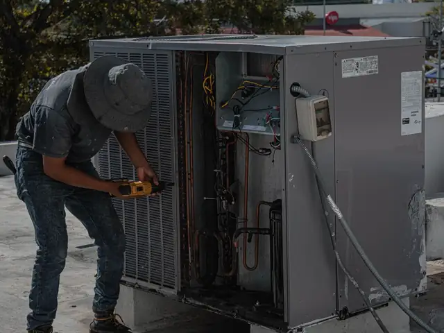 Technician servicing a central air conditioner condenser