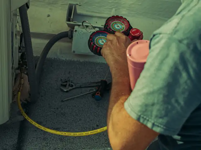 Technician checking refrigerant pressure during seasonal HVAC maintenance